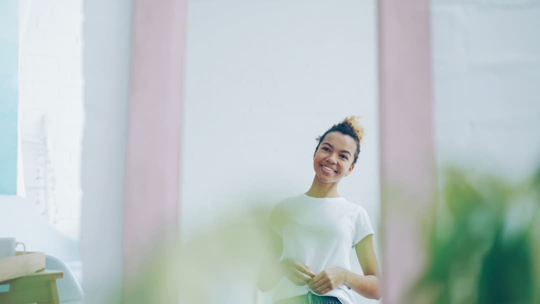 Young woman smiling confidently at her reflection in a mirror